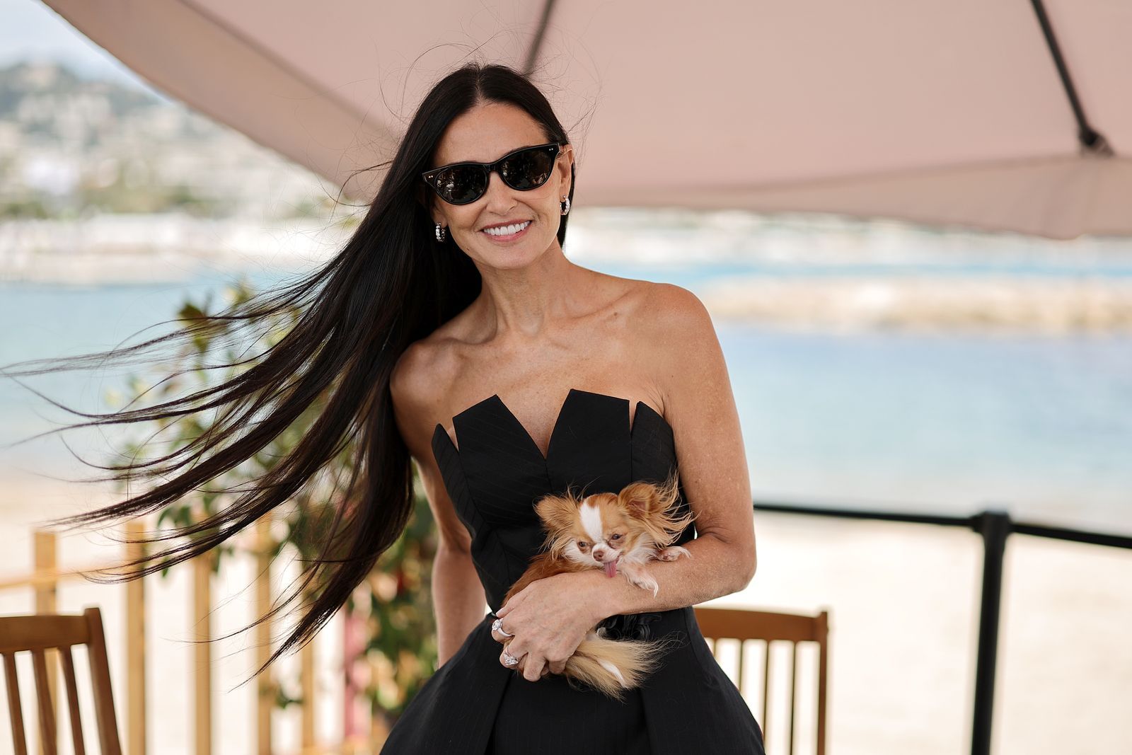 Pilaf carried in the arm of someone wearing black couture beside the sea.